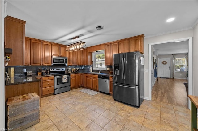 202 Stokes Forest Dr, King, NC 27021 - kitchen featuring appliances with stainless steel finishes, a sink, brown cabinetry, backsplash, and ornamental molding