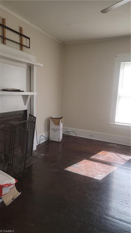 living area featuring baseboards, ornamental molding, and wood finished floors