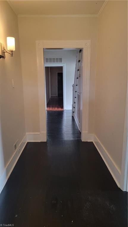 hallway with ornamental molding, baseboards, and dark wood-style floors