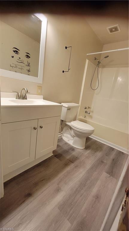 full bath with vanity, shower / bath combination, toilet, visible vents, and wood finished floors