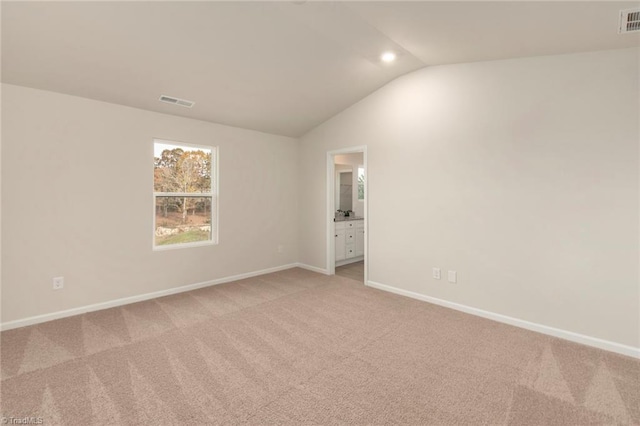 unfurnished room featuring light colored carpet and vaulted ceiling