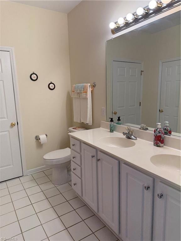 bathroom with tile patterned flooring, double vanity, toilet, and a sink