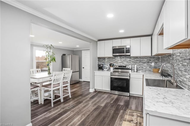 kitchen featuring sink, appliances with stainless steel finishes, ornamental molding, white cabinets, and decorative backsplash