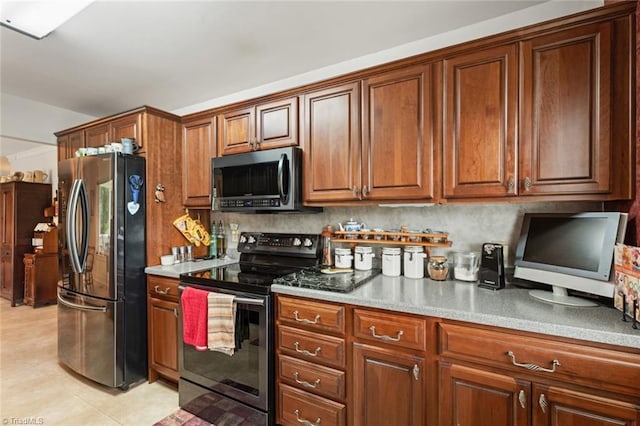 kitchen featuring light tile patterned floors, stainless steel appliances, tasteful backsplash, and brown cabinetry