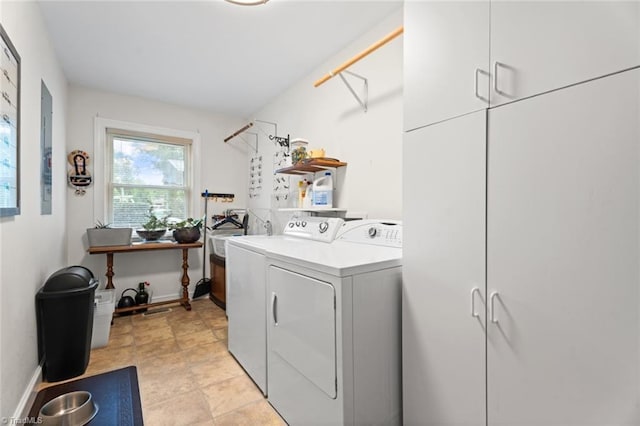 laundry room featuring baseboards, cabinet space, and washer and clothes dryer