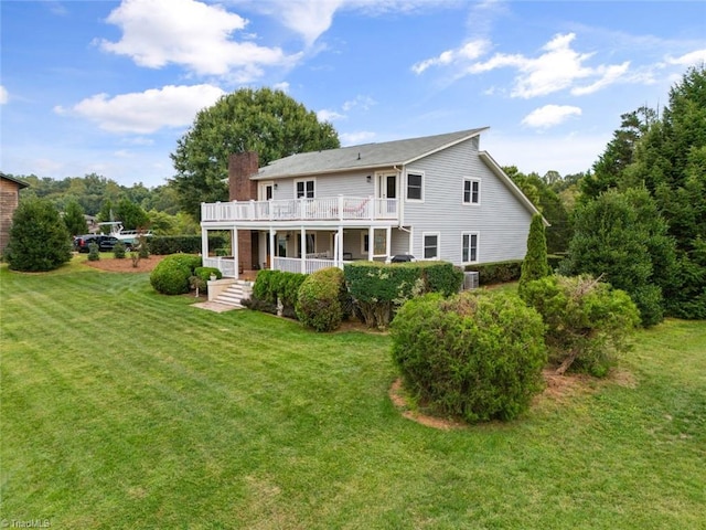 rear view of property with a balcony, a chimney, and a yard