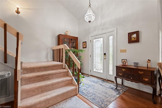 entryway with stairway, baseboards, high vaulted ceiling, and wood finished floors