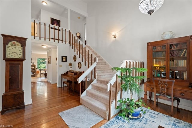 stairway with baseboards, a towering ceiling, and wood finished floors