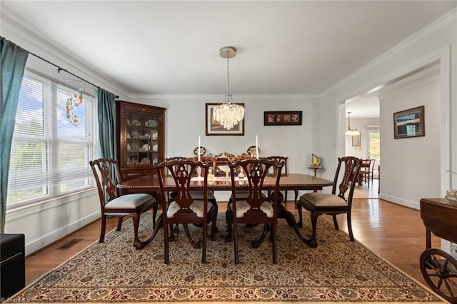 dining area featuring visible vents, wood finished floors, baseboards, and ornamental molding