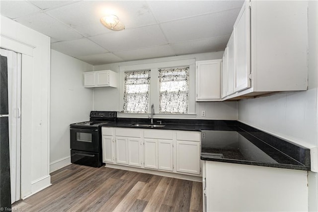 kitchen featuring white cabinetry, black electric range, sink, a paneled ceiling, and wood-type flooring