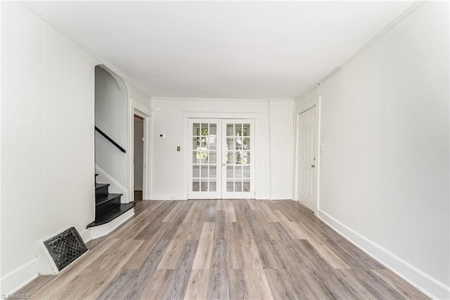 unfurnished living room featuring crown molding, light hardwood / wood-style flooring, and french doors