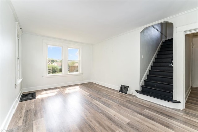 unfurnished living room with light wood-type flooring and ornamental molding