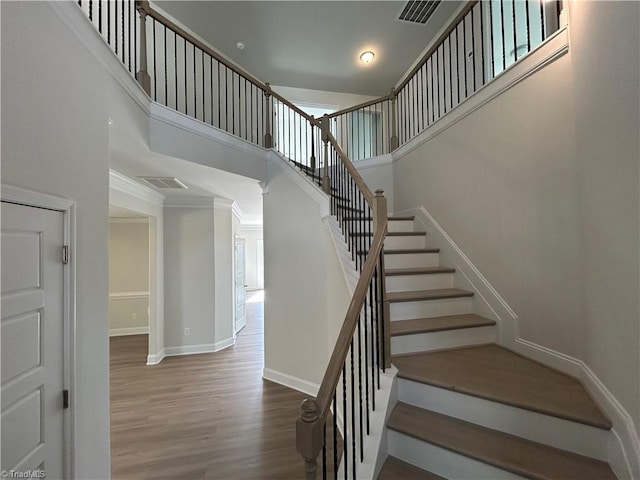 staircase with a high ceiling and wood-type flooring