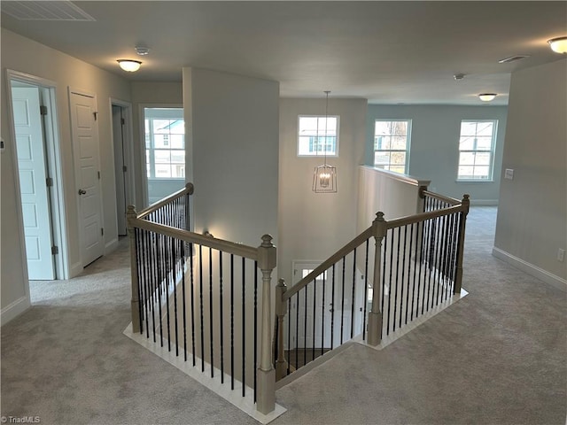 stairway with carpet floors and a notable chandelier