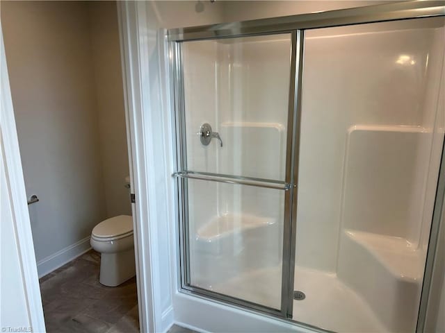 bathroom featuring a shower with shower door and toilet