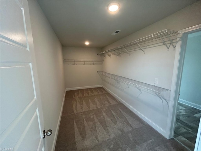 walk in closet with dark colored carpet