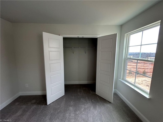 unfurnished bedroom with dark carpet and a closet