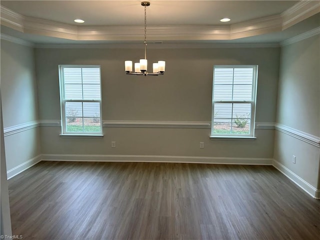 spare room featuring crown molding, dark hardwood / wood-style floors, a raised ceiling, and a chandelier