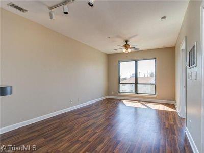 411 W Washington St Unit 309, Greensboro, NC 27401 - empty room with a ceiling fan, dark wood-style flooring, and baseboards