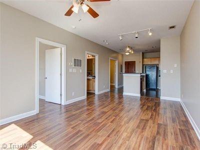 411 W Washington St Unit 309, Greensboro, NC 27401 - unfurnished living room with a ceiling fan, wood finished floors, baseboards, and track lighting
