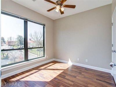 411 W Washington St Unit 309, Greensboro, NC 27401 - empty room with healthy amount of natural light, baseboards, a ceiling fan, and wood finished floors