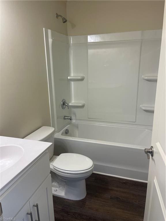 full bathroom with hardwood / wood-style flooring, washtub / shower combination, vanity, and toilet