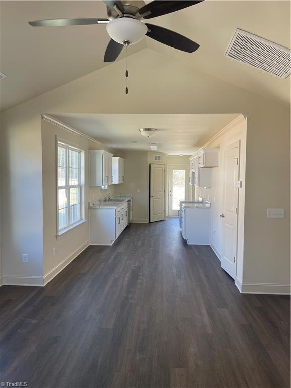 unfurnished living room featuring lofted ceiling, dark hardwood / wood-style floors, sink, and a wealth of natural light