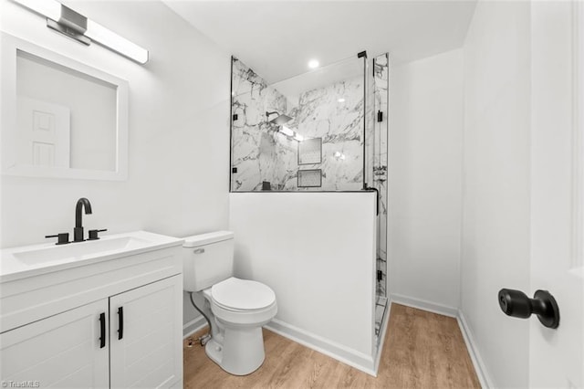 full bath with vanity, wood finished floors, baseboards, a marble finish shower, and toilet