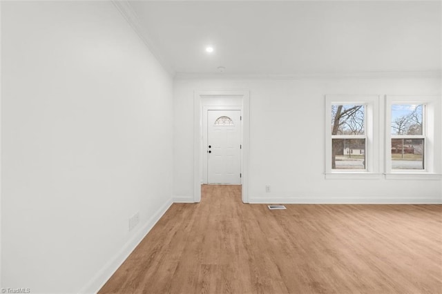 empty room featuring light wood-style floors, baseboards, and ornamental molding