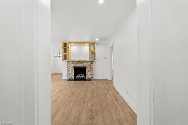 unfurnished living room featuring wood finished floors, baseboards, visible vents, a fireplace, and ornamental molding