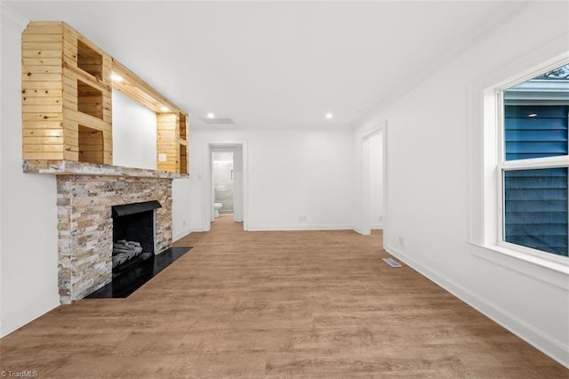 unfurnished living room with wood finished floors, a fireplace, and baseboards