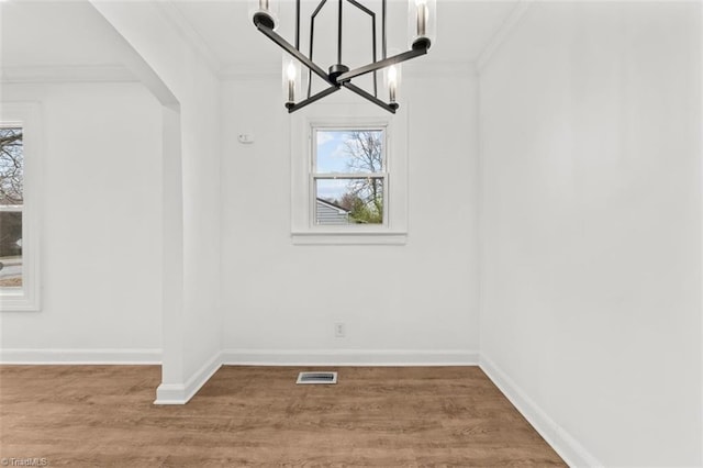 unfurnished dining area with a wealth of natural light, visible vents, wood finished floors, and crown molding