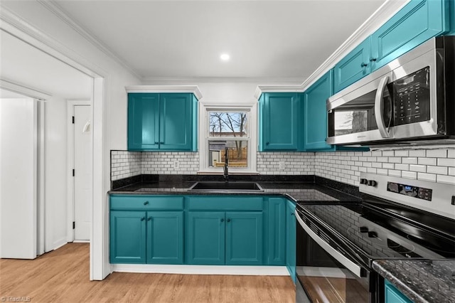 kitchen featuring crown molding, blue cabinets, appliances with stainless steel finishes, and a sink