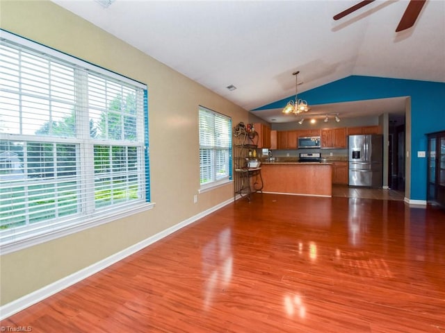 kitchen with stainless steel appliances, dark hardwood / wood-style flooring, ceiling fan with notable chandelier, pendant lighting, and vaulted ceiling