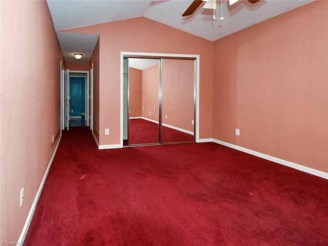 unfurnished bedroom with lofted ceiling, a closet, dark colored carpet, and ceiling fan