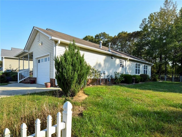 view of side of property featuring an attached garage, driveway, fence, and a yard