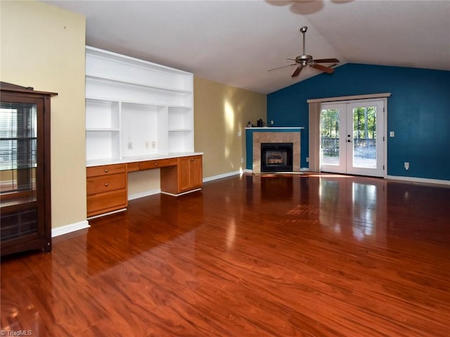 unfurnished living room with ceiling fan, vaulted ceiling, built in desk, a fireplace, and dark hardwood / wood-style floors