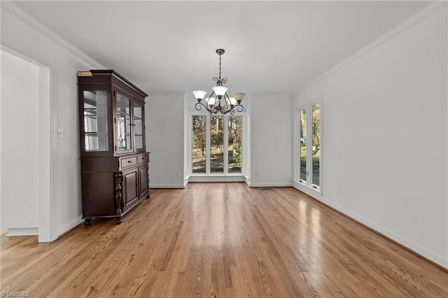 unfurnished dining area featuring baseboards, a notable chandelier, ornamental molding, and light wood finished floors