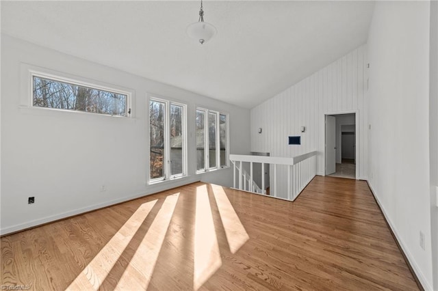 spare room with wood finished floors, baseboards, and high vaulted ceiling