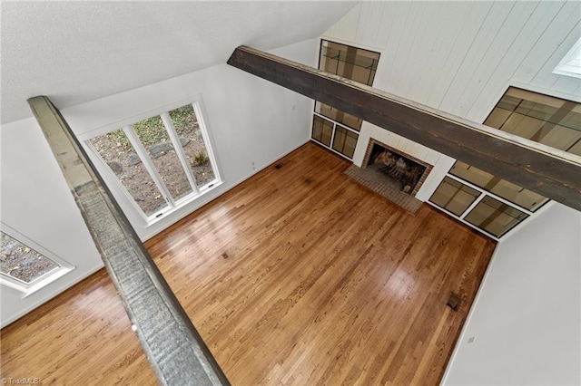 living area featuring vaulted ceiling, a brick fireplace, and wood finished floors