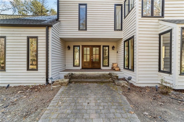 entrance to property featuring french doors and roof with shingles