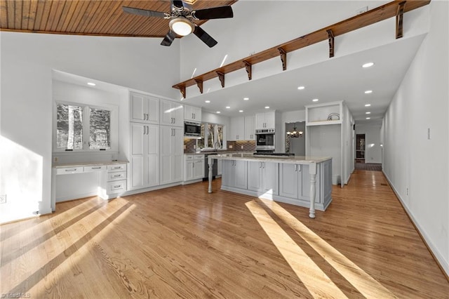 kitchen with light countertops, light wood-style flooring, stainless steel appliances, white cabinetry, and a ceiling fan