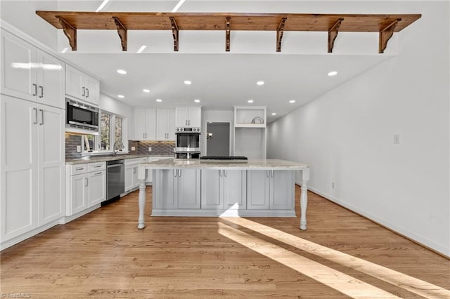 kitchen featuring a kitchen island, backsplash, appliances with stainless steel finishes, and white cabinetry