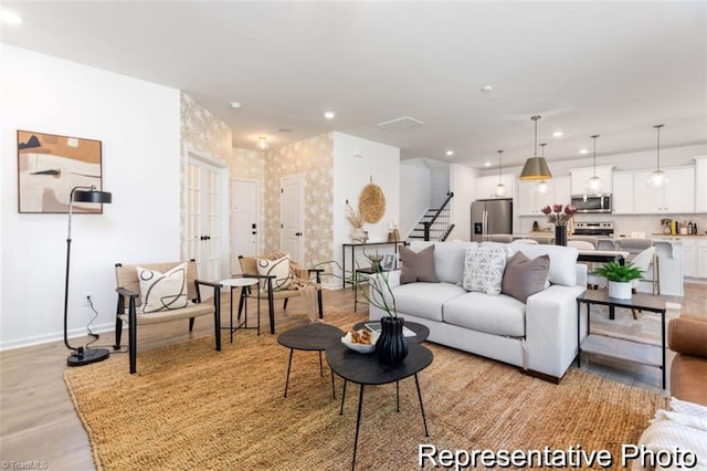 living area featuring light wood-type flooring, baseboards, stairway, and recessed lighting