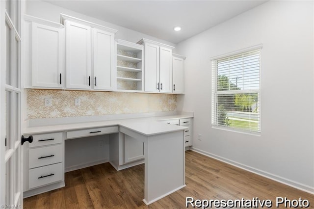 unfurnished office featuring baseboards, built in desk, dark wood-style flooring, and recessed lighting