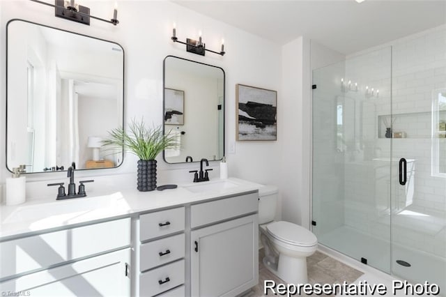 full bath featuring double vanity, a stall shower, a sink, and toilet