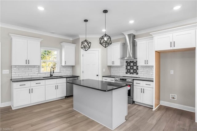 kitchen with stainless steel appliances, sink, wall chimney range hood, white cabinetry, and hanging light fixtures