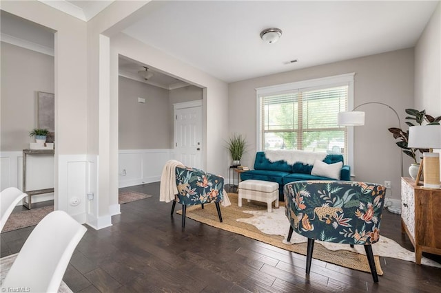 living room with dark wood-style flooring, wainscoting, and ornamental molding