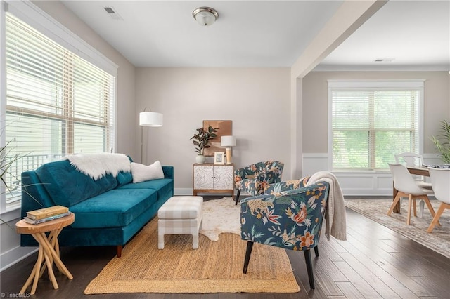 living room with wainscoting, dark wood finished floors, and visible vents