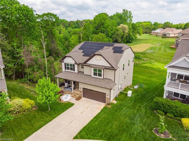 view of front of home with an attached garage, driveway, a front yard, and solar panels